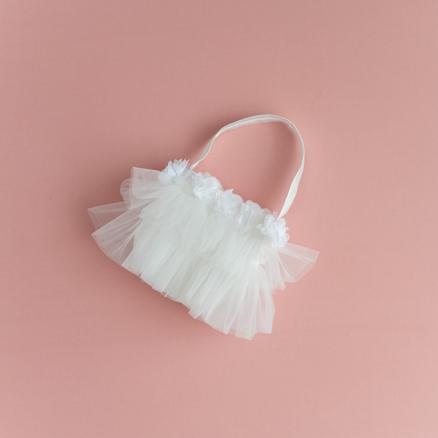 White tulle flower girl basket bag with soft fabric flowers and ribbon handle, styled as a matching wedding accessory.