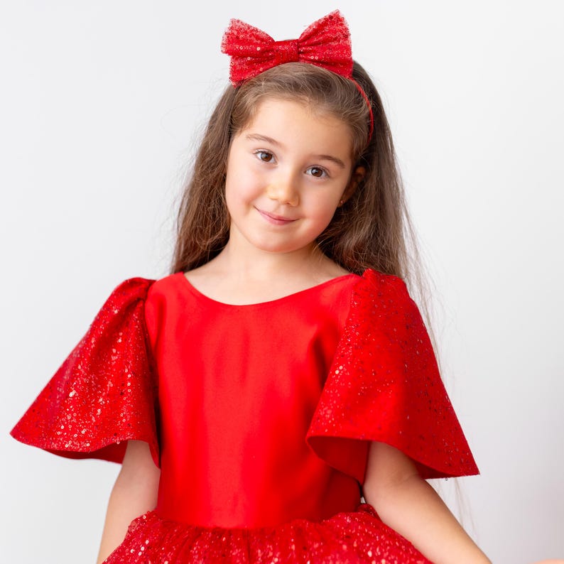 Portrait view of girl in red satin flower girl dress with short flutter sleeves