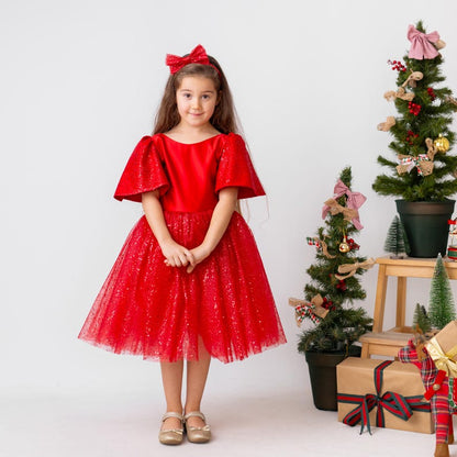 Red satin flower girl dress with sparkly tulle skirt and short flutter sleeves, shown in a Christmas studio setting.