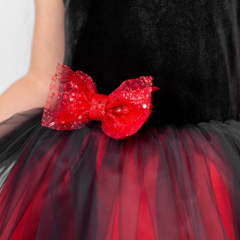 Close up of red bow detail on black and red velvet flower girl dress with layered tulle skirt
