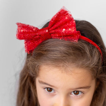 Close-up of a red sparkly bow headband styled with a red and black sparkly Christmas holiday flower girl dress.