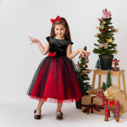 Girl wearing a red and black sparkly Christmas holiday dress with a velvet bodice and layered tulle skirt, festive studio setting.