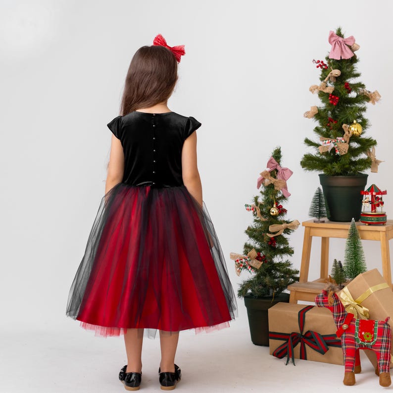 Full back view of red and black velvet flower girl dress with layered tulle skirt in holiday studio setting
