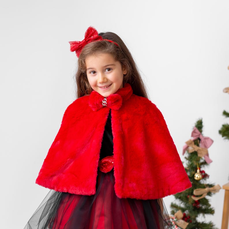 Girl wearing red faux fur cape over red and black velvet flower girl dress for holiday occasions