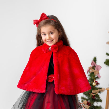 Girl wearing red faux fur cape over red and black velvet flower girl dress for holiday occasions