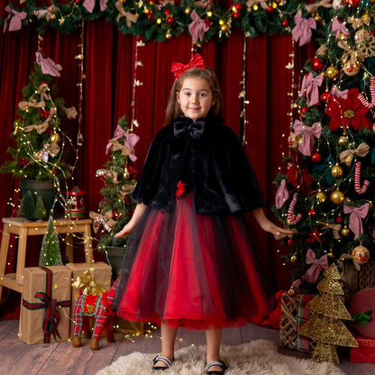 Girl wearing red and black velvet flower girl dress with black faux fur cape in festive holiday studio setting