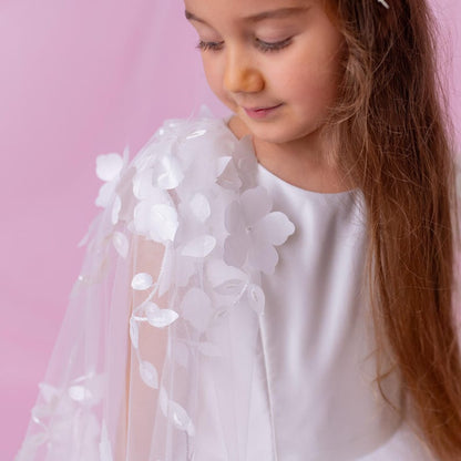Close-up of a young girl in a white personalized flower girl dress with a floral cape, showing the delicate flower details.