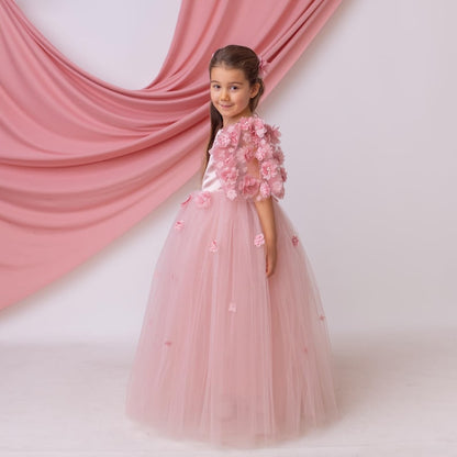 Side view of blush satin flower girl dress showcasing a flowing tulle skirt and textured floral appliqué sleeves