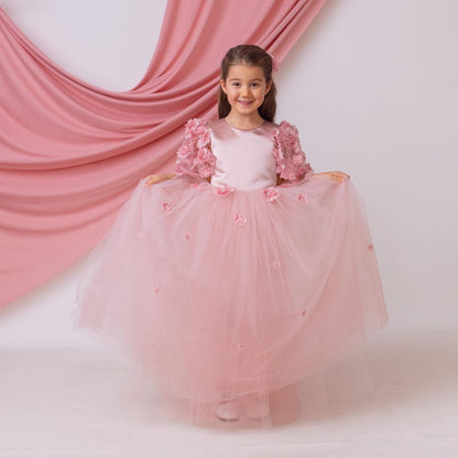 Front view of blush satin flower girl dress holding the tulle skirt on both sides, highlighting volume and floral embellishments