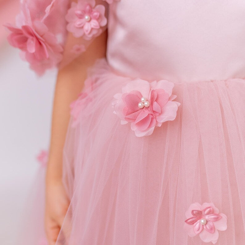 Detail view of blush flower girl dress highlighting the waistline with floral appliqué accents on a soft layered tulle skirt