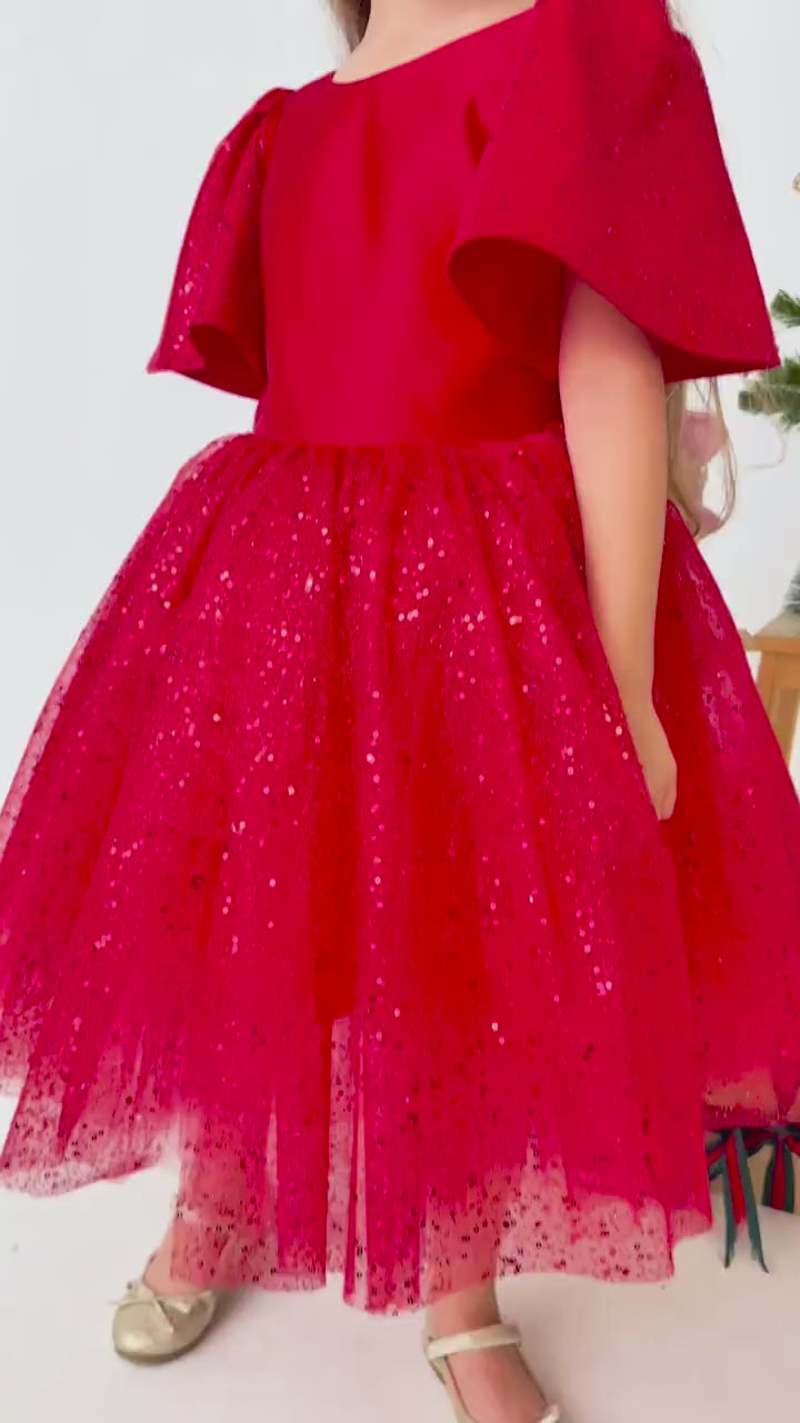 Red satin flower girl dress shown in motion with layered tulle skirt and elegant silhouette
