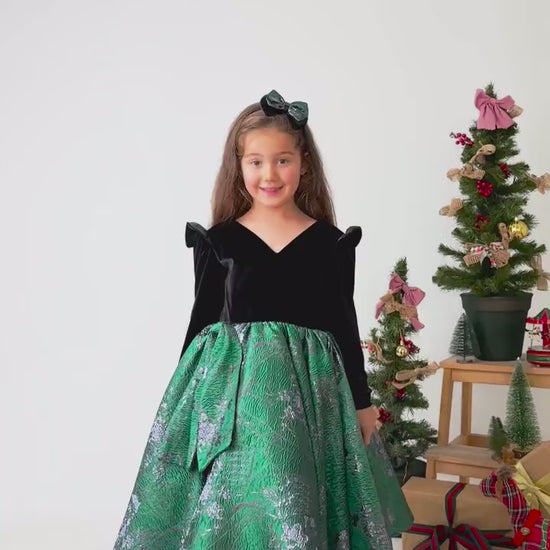 Video showing emerald green velvet flower girl dress in motion with full skirt and styling details
