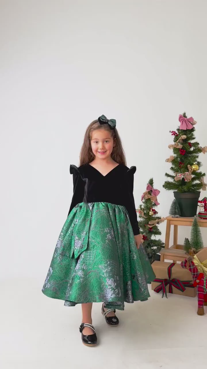 Video showing emerald green velvet flower girl dress in motion with full skirt and styling details
